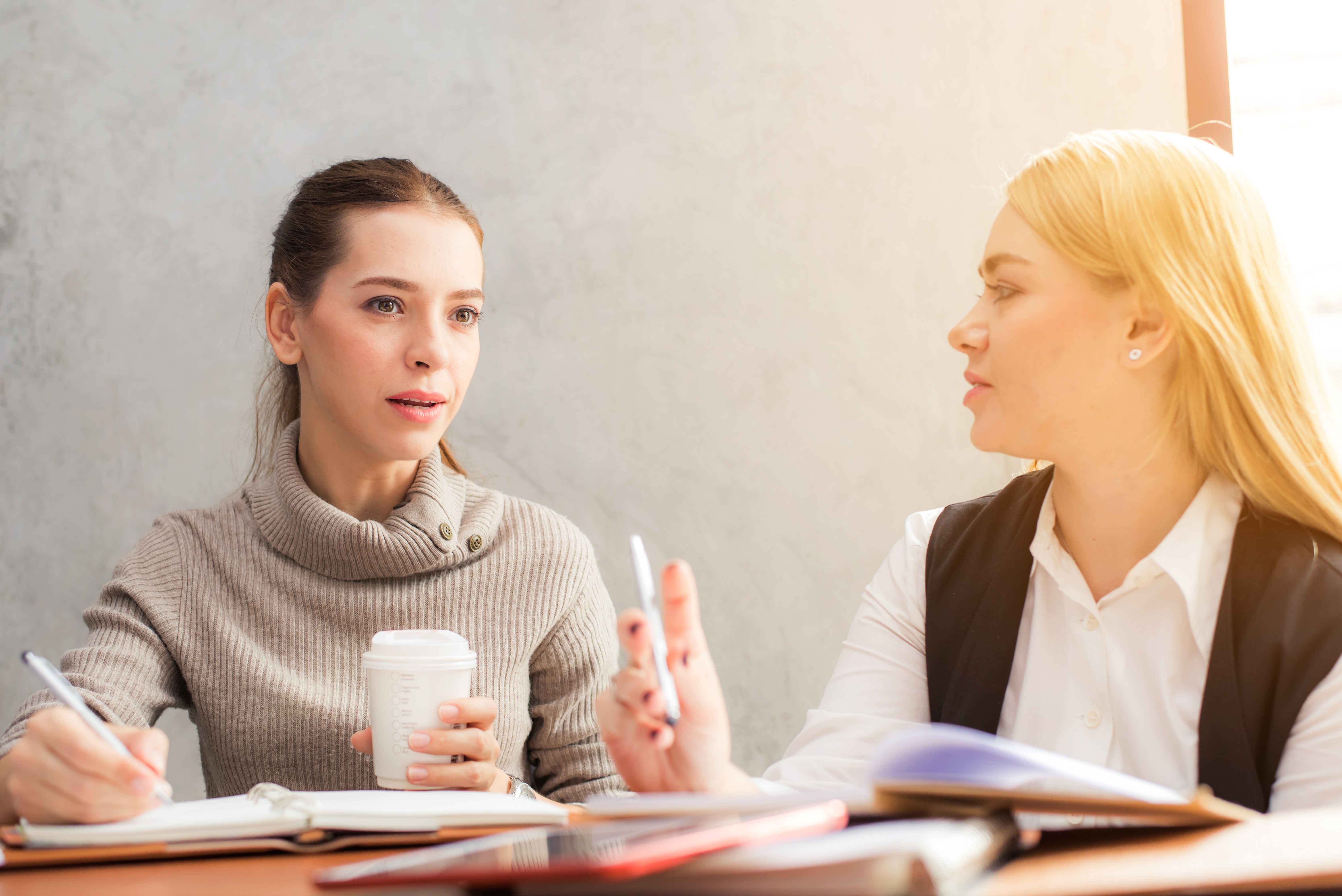 Two friends sitting at a table discussing work.