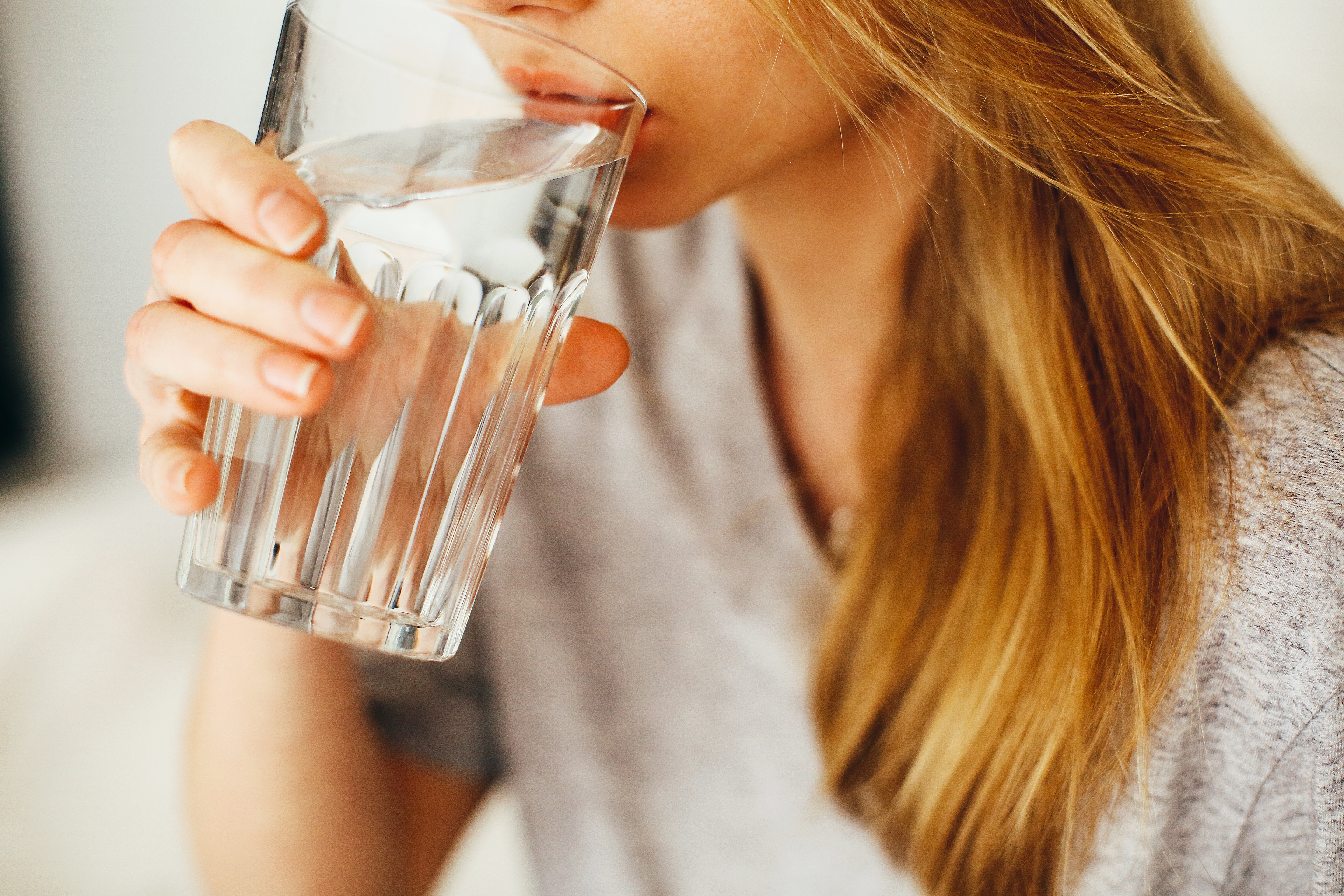 Woman drinking from a large glass of water.