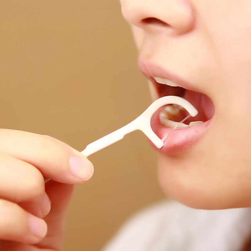 Woman flossing her teeth with a flosser.