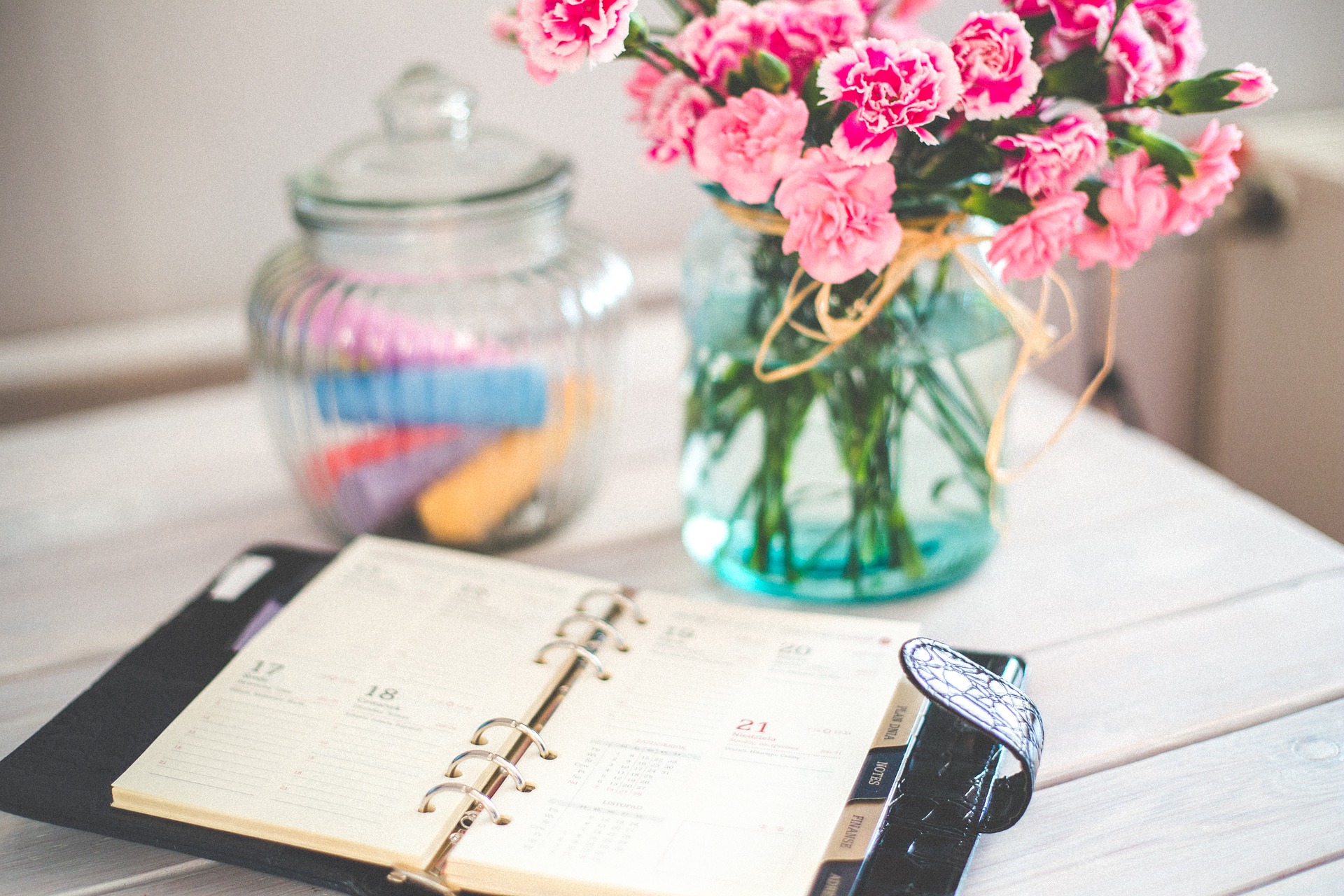 Jar of flowers on a desk next to a planner.