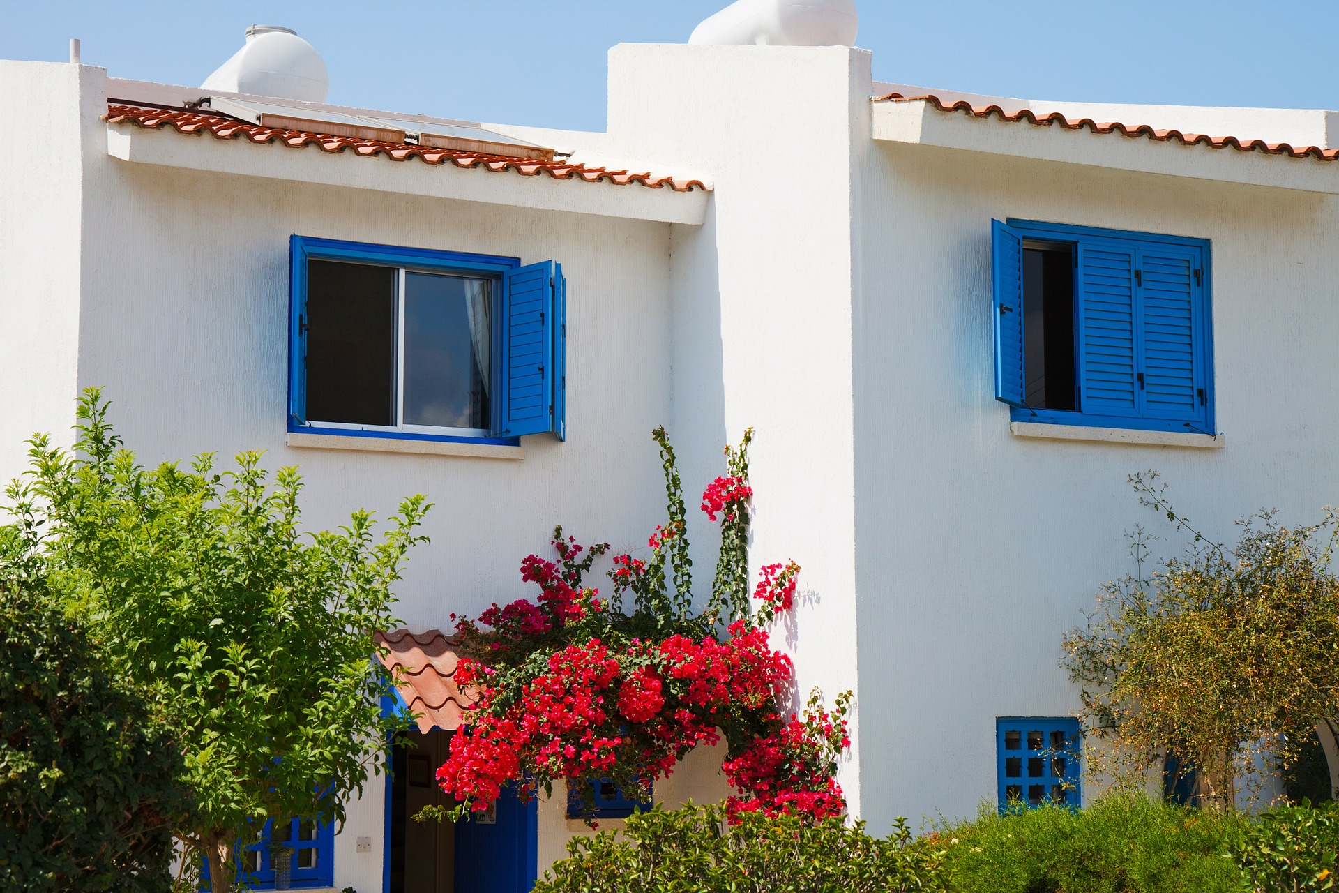 White house with blue shutters and a tile roof.