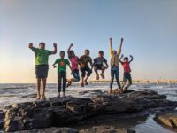 Kids jumping on a rocky jetty at the beach