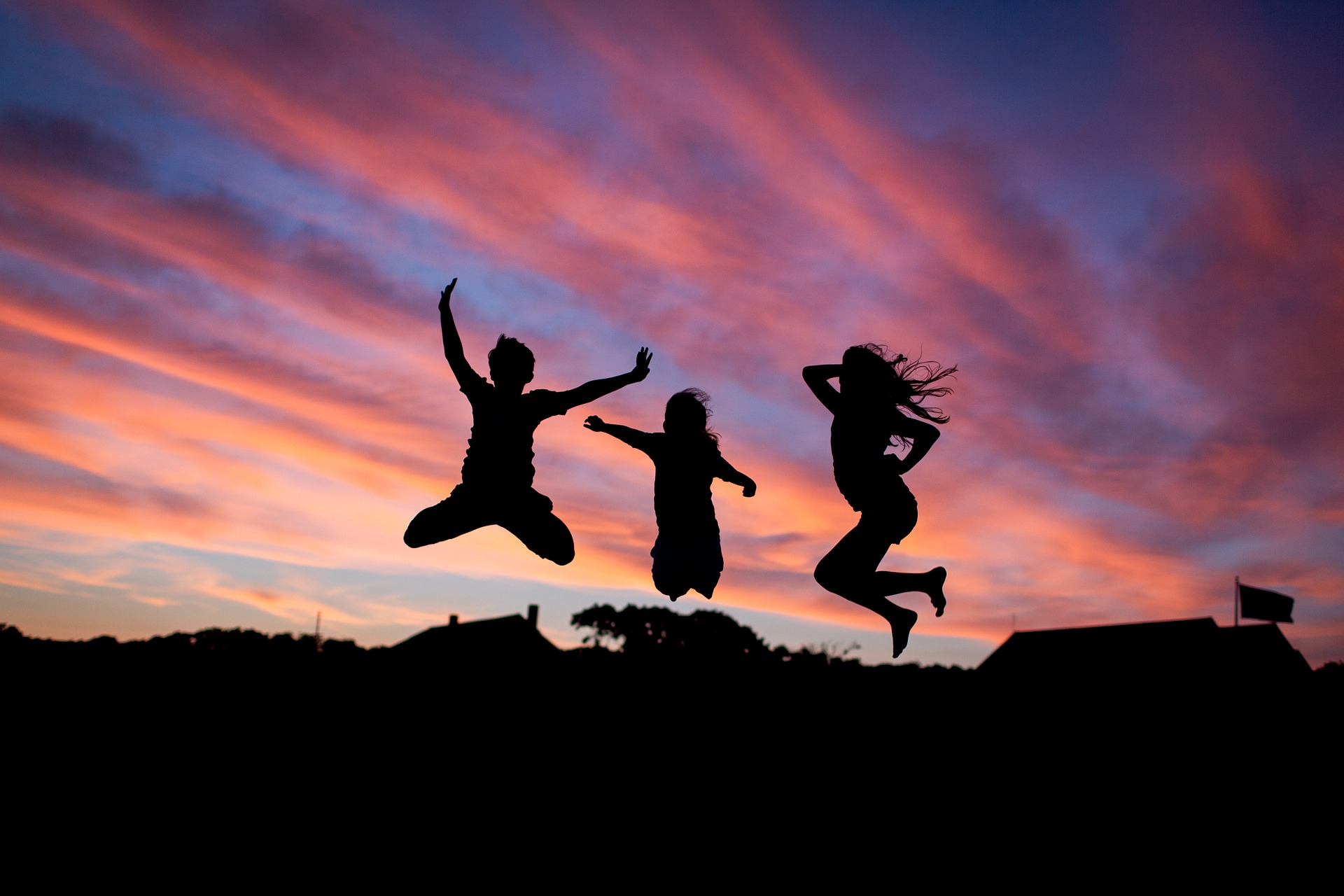 Three people jumping in the air during a pretty sunset.