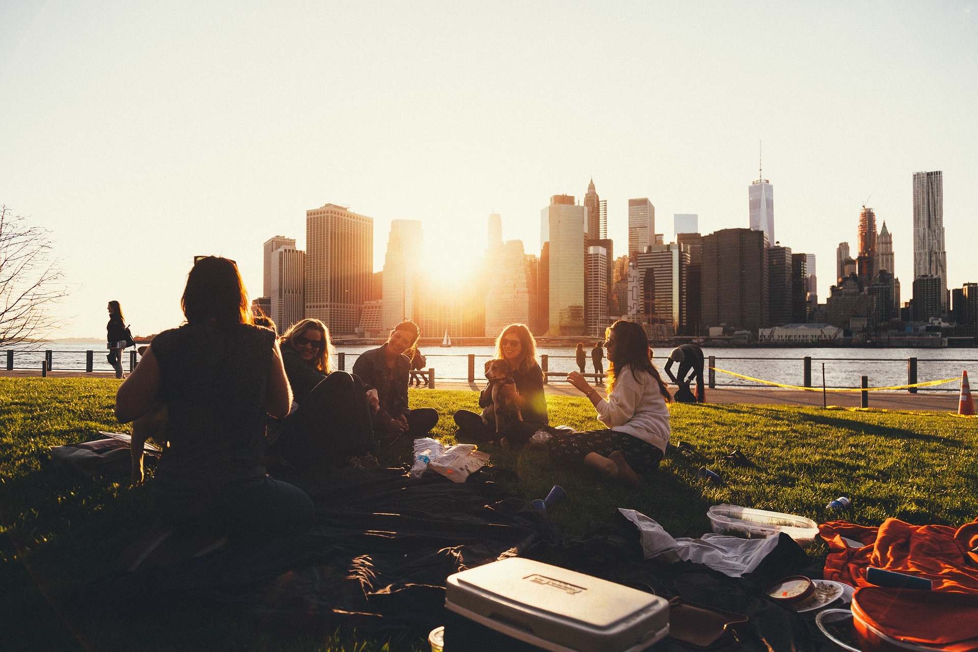 Friends having a picnic overlooking a city during a sunset.