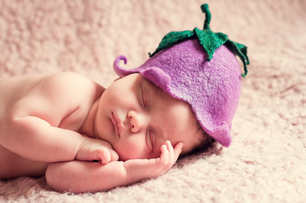 Newborn posed for a photo with a berry hat.