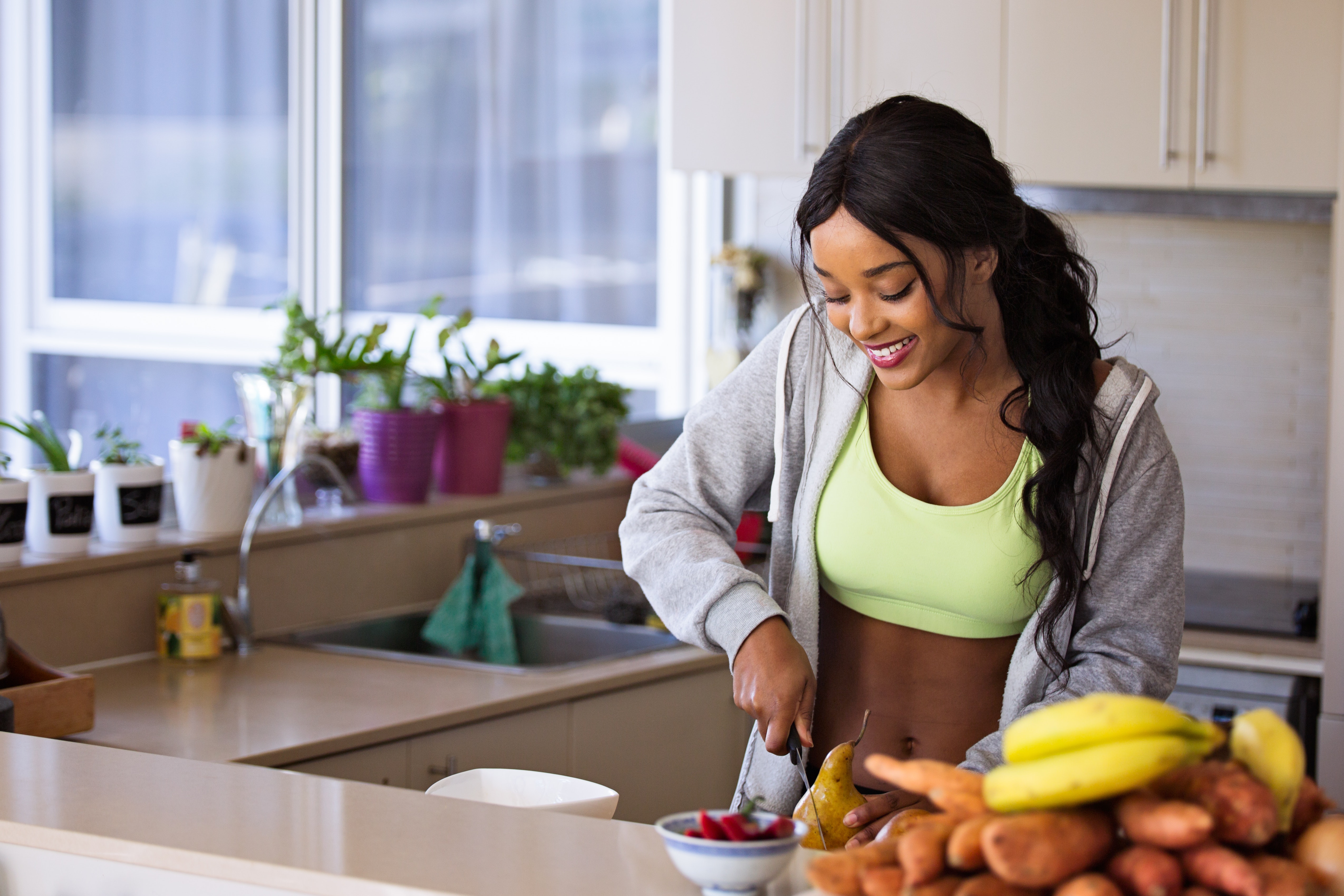 Happy woman preparing food wearing fitness clothing.