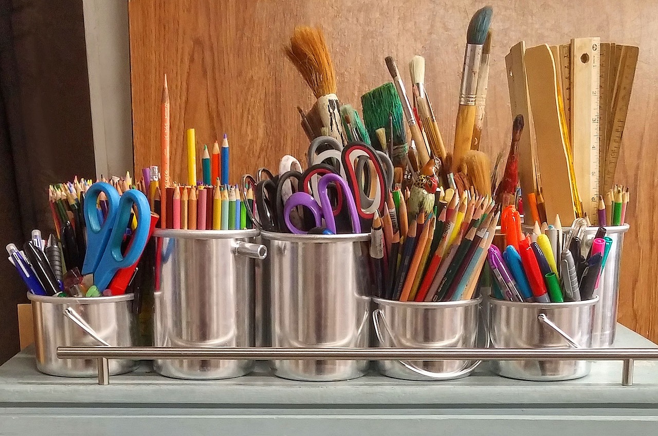 Variety of art supplies in metal jars.