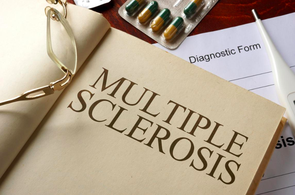 Book with the words "Multiple Sclerosis" and pills next to it.