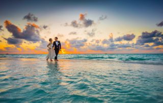 Newlywed couple walking on the beach in a sunsert