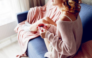 Woman in a cozy pink sweater relaxing on a blue couch