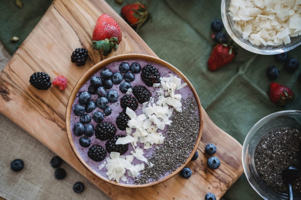 Smoothie bowl with a purple smoothie and a variety of toppings, including blueberries, chia seeds, and coconut flakes