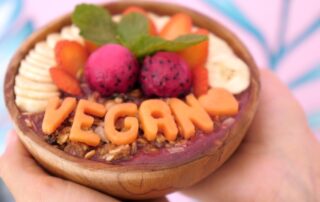 Smoothie bowl with the word vegan spelled out in fruit
