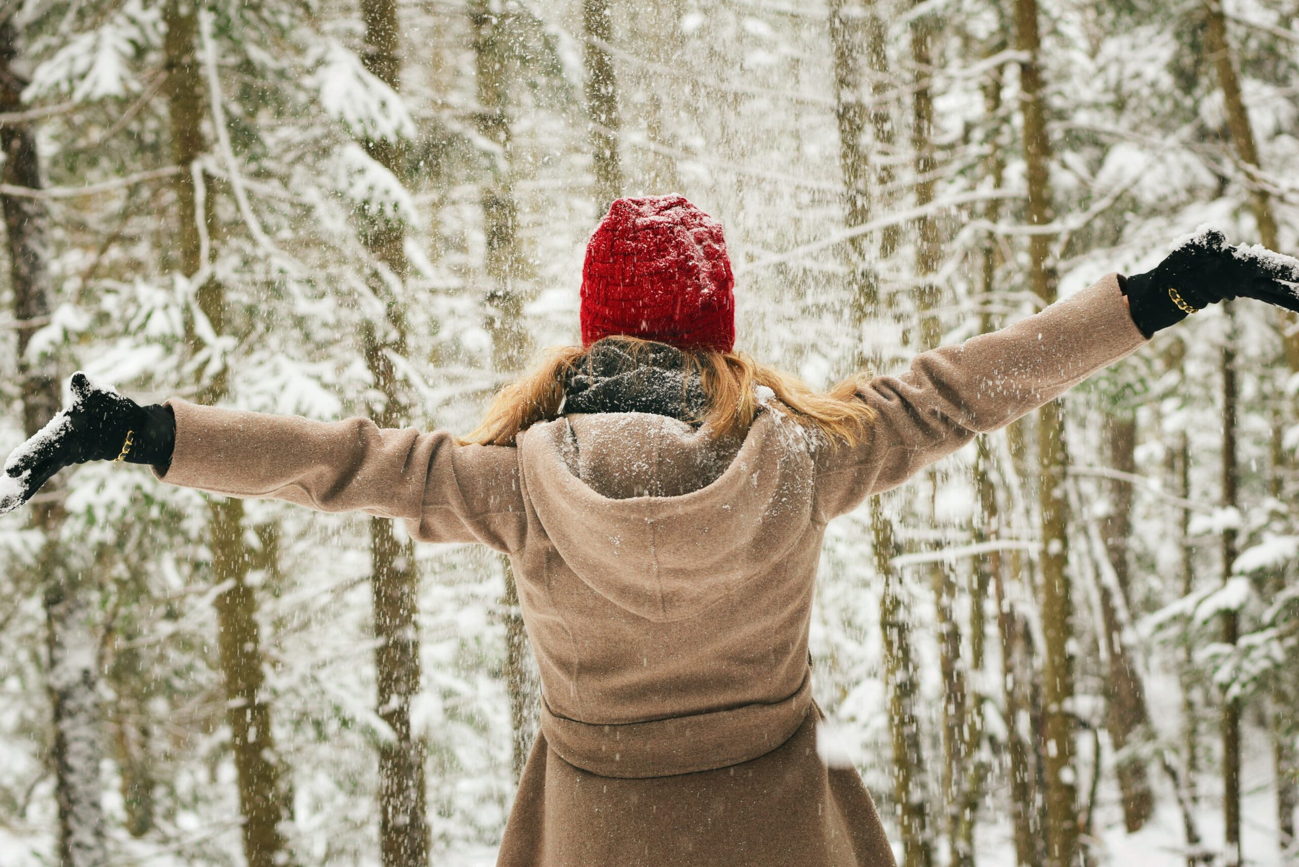 Woman with her arms outstretched in a snowy forest