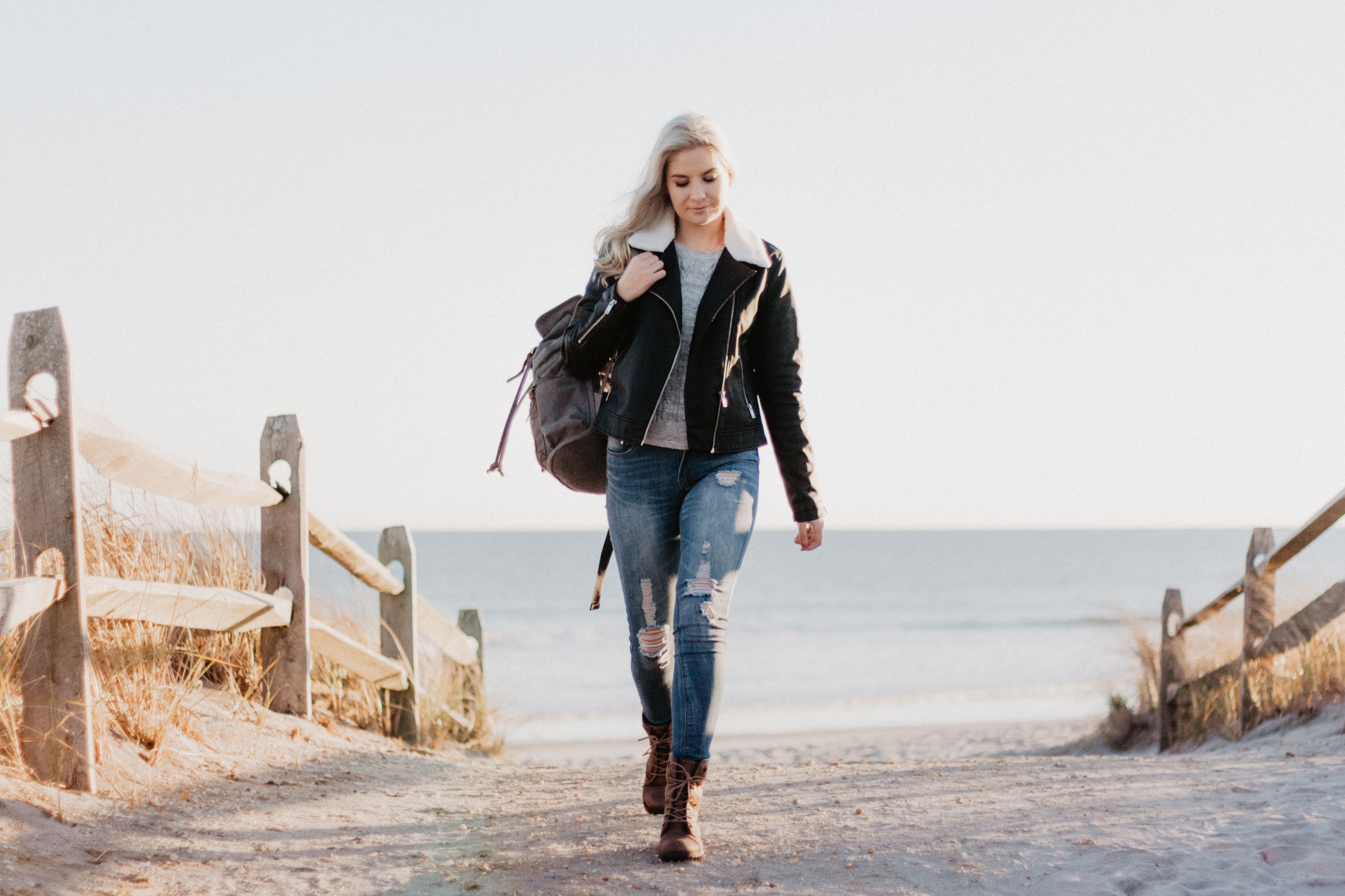 Woman walking off the beach in a black leather jacket