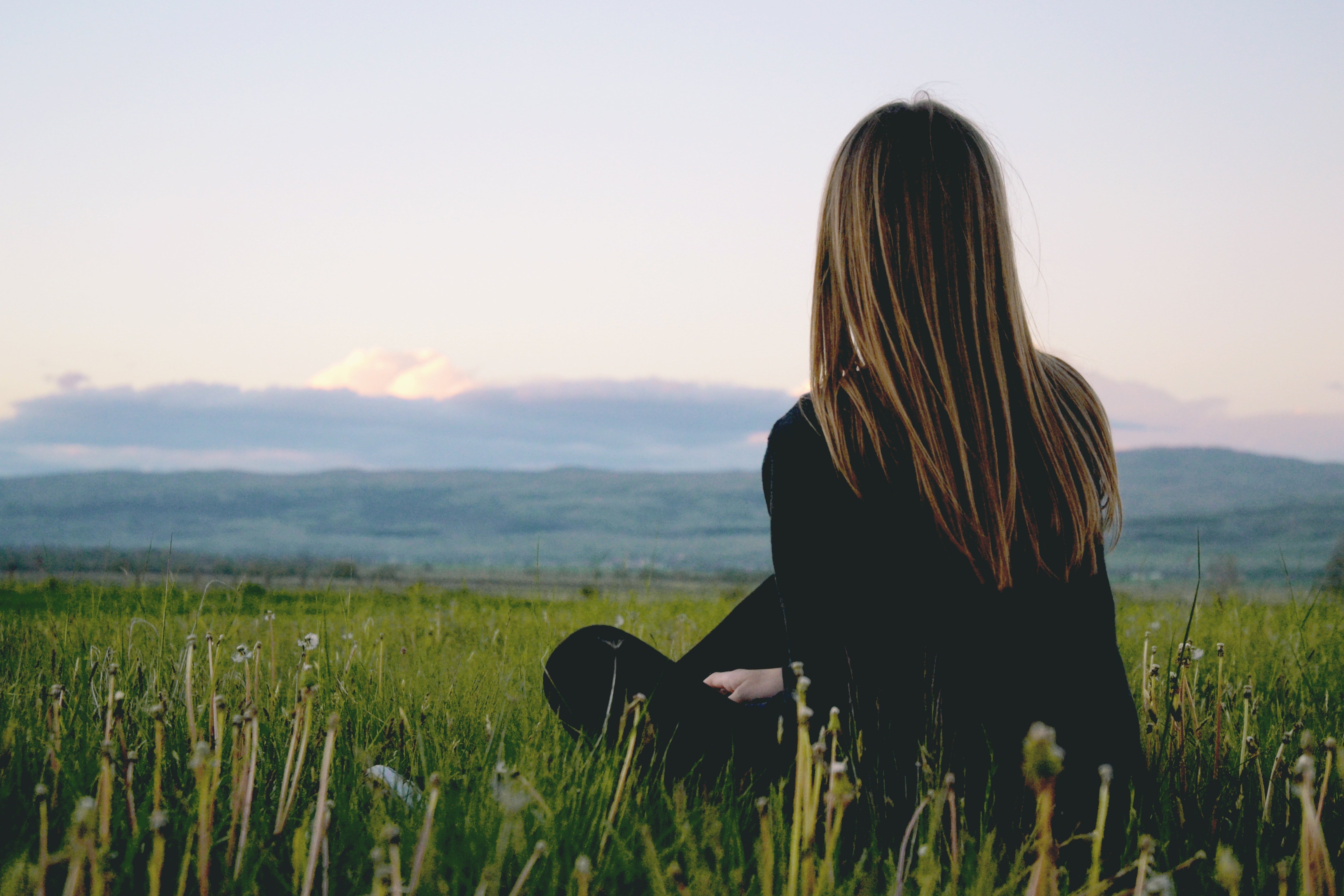 Woman sitting in a field looking at mountains