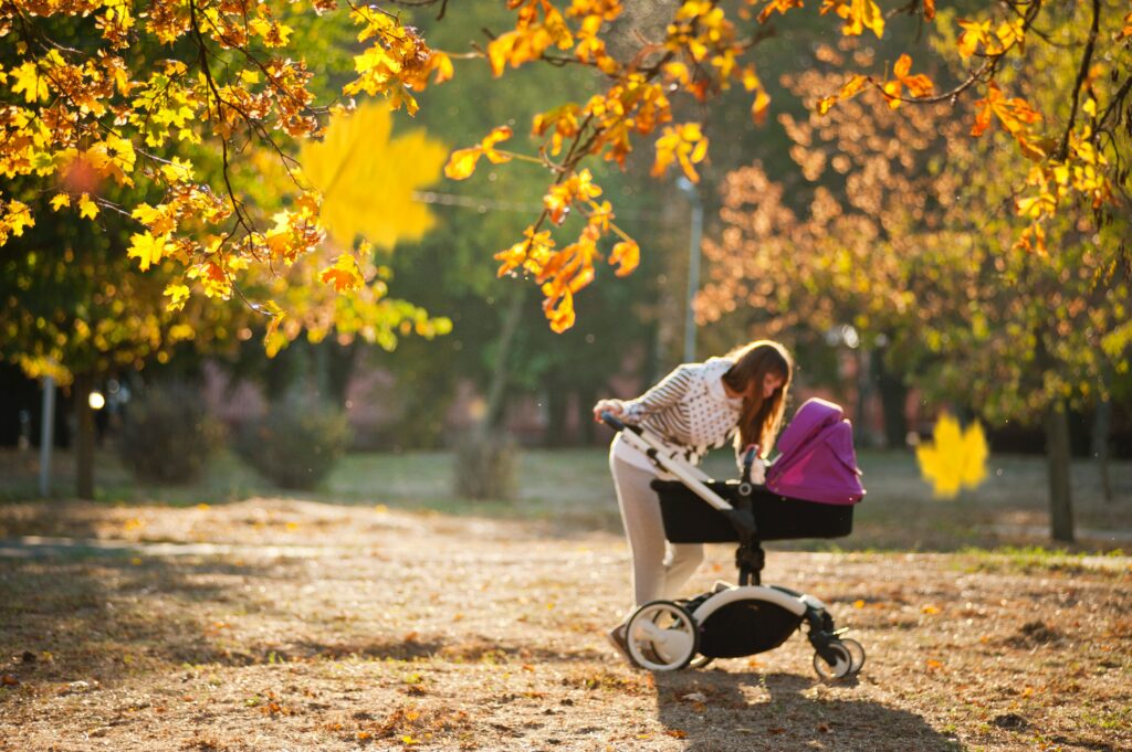 Lovely fall scene with a mom checking on her baby in a stroller