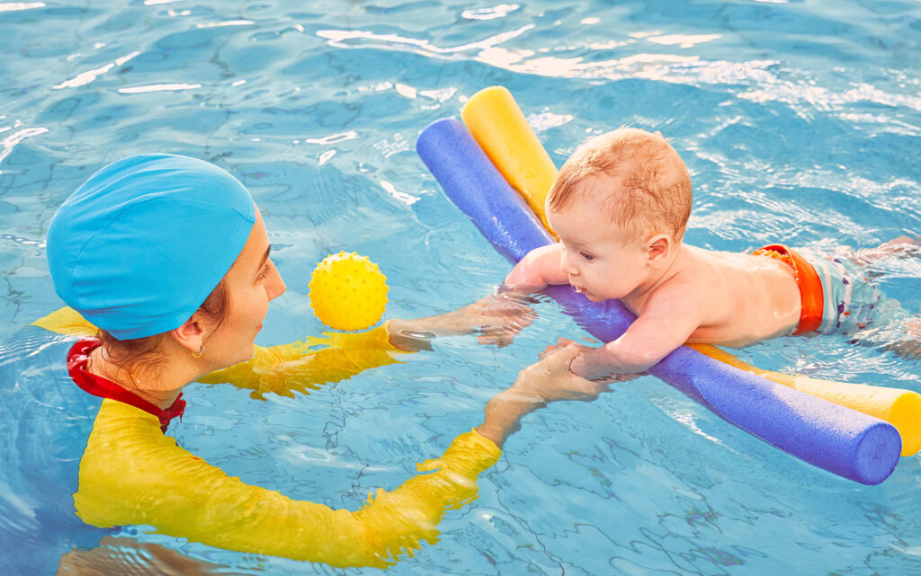 Baby in a the pool with a swim instructor