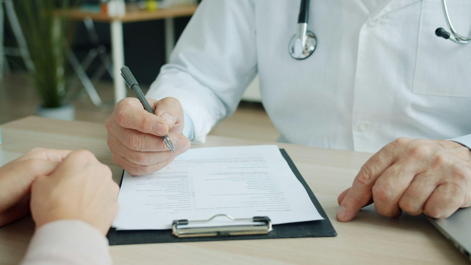 Doctor writing on a clipboard at a desk.